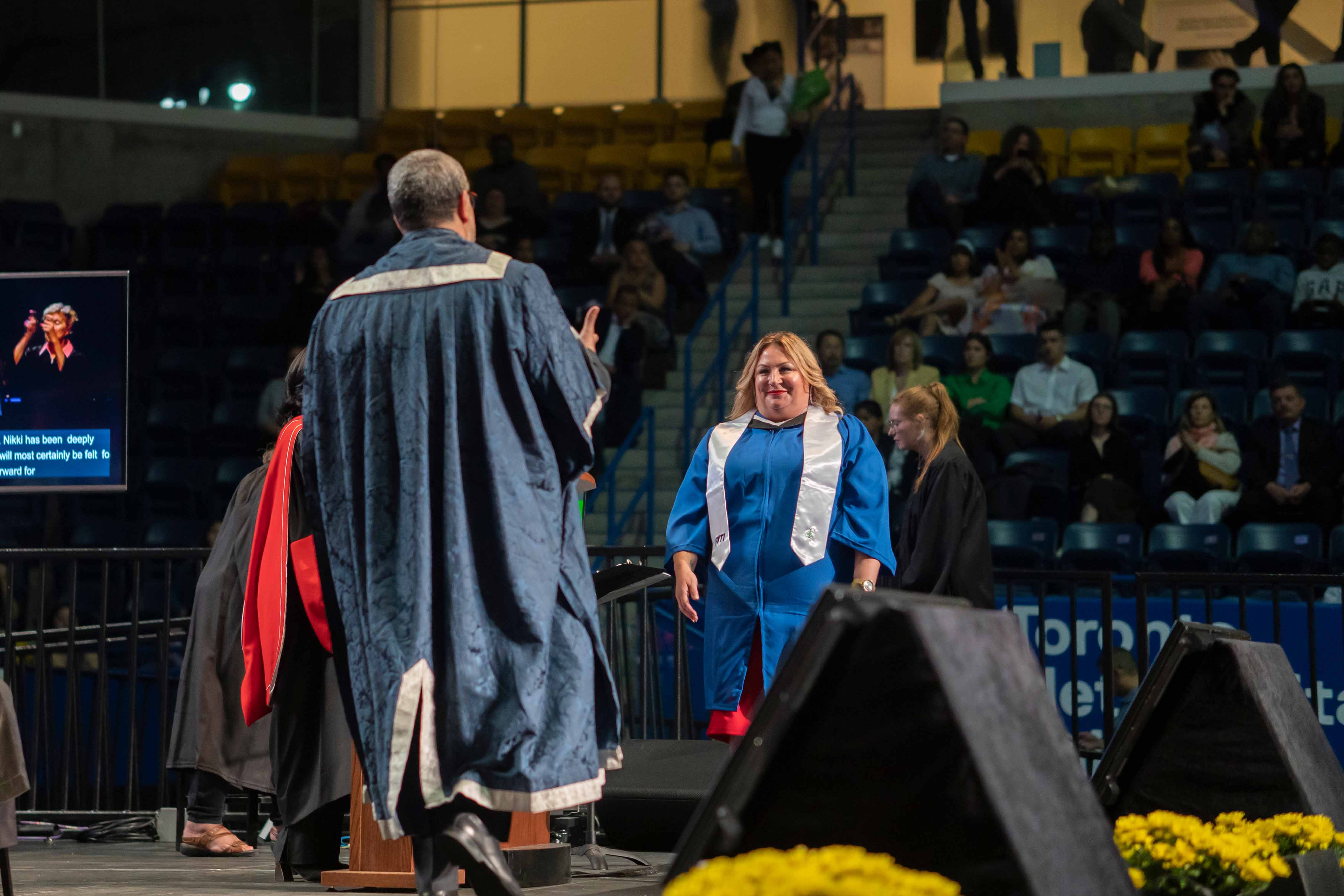 Nikki van Oirschot walking the convocation stage towards Mohamed Lachemi