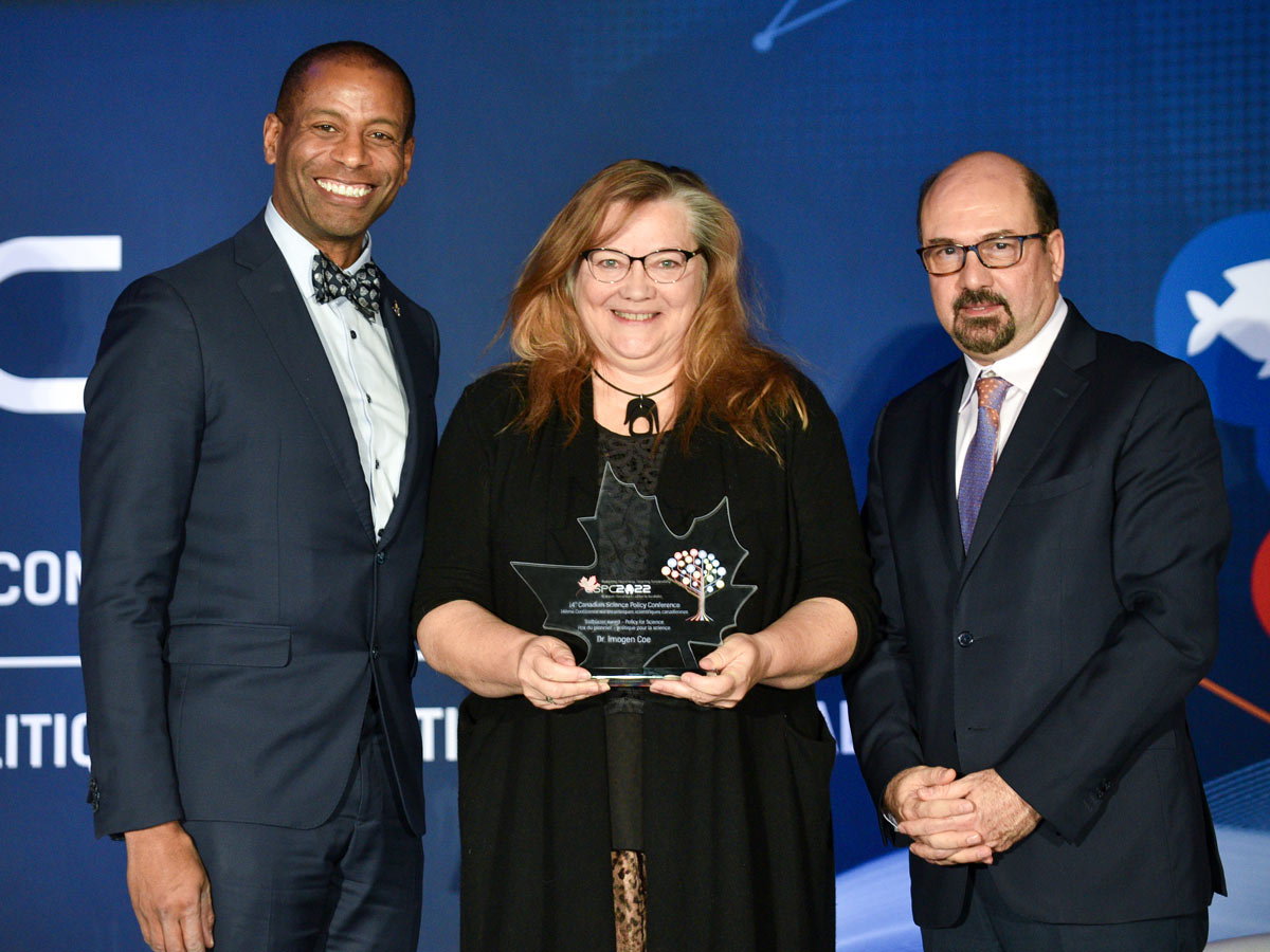 Professor Imogen Coe (centre) holds a glass maple leaf shaped award at the CSPC annual conference award ceremony. She is pictured with MP Greg Fergus (left) and CSPC CEO and President Mehrdad Hariri (right)