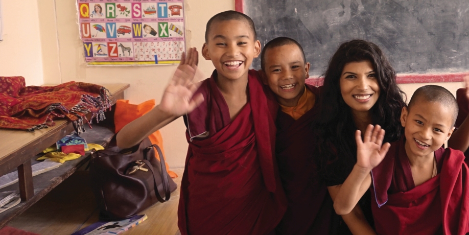 Student in classroom with smiling boys wearing maroon robes