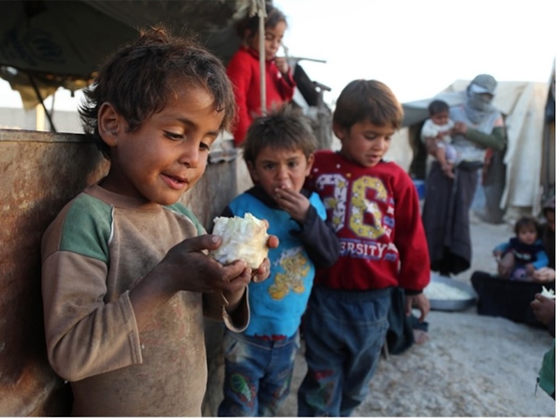 Syrian children eating bread in a refugee camp