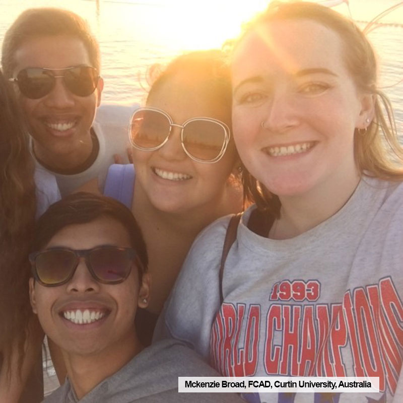 Toronto Metropolitan University FCAD student, Mckenzie Broad, poses with friends in front of a sunset while on exchange at Curtin University, Australia.