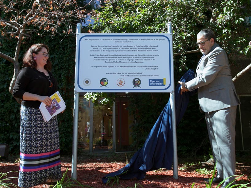 Social work student Sarah Dennis, left, and Ryerson President Mohamed Lachemi unveil the plaque