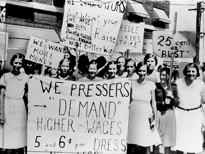 An archival image of a group of women on strike with banners and signs.