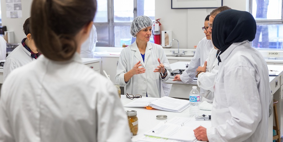 Profesor instructings students in lab coats