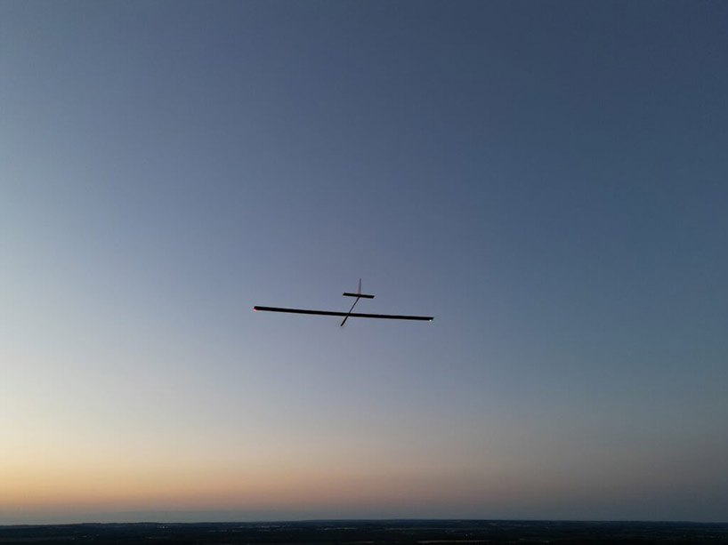 An unmanned airplane flies in an evening sky