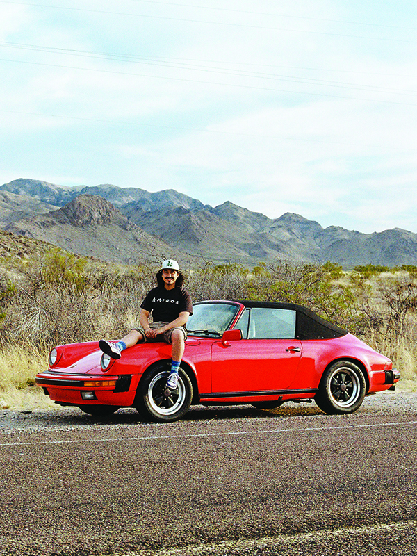 Angel Fonseca sitting on the hood of a 1985 Porsche 911