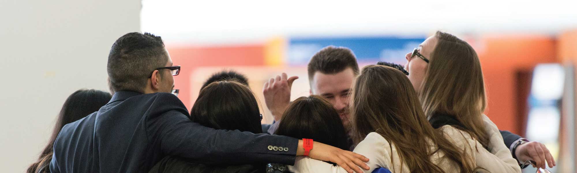 A group of eight students hugging in a group circle.