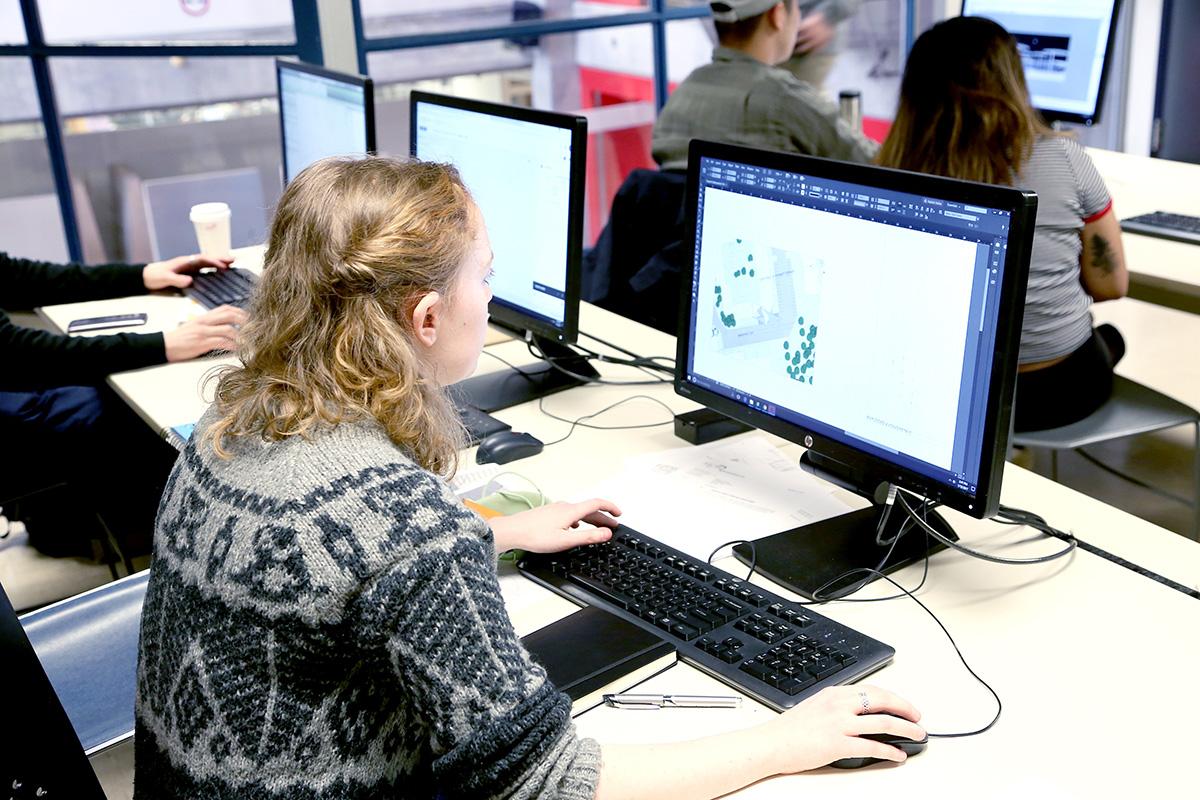 A student works on an architectural rendering on a desktop computer. 