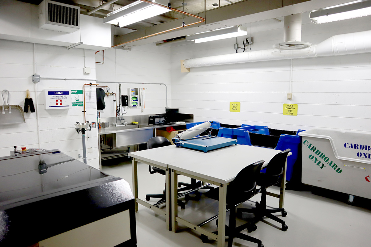 An industrial-sized sink, large containers for materials and a worktable in the lab. 