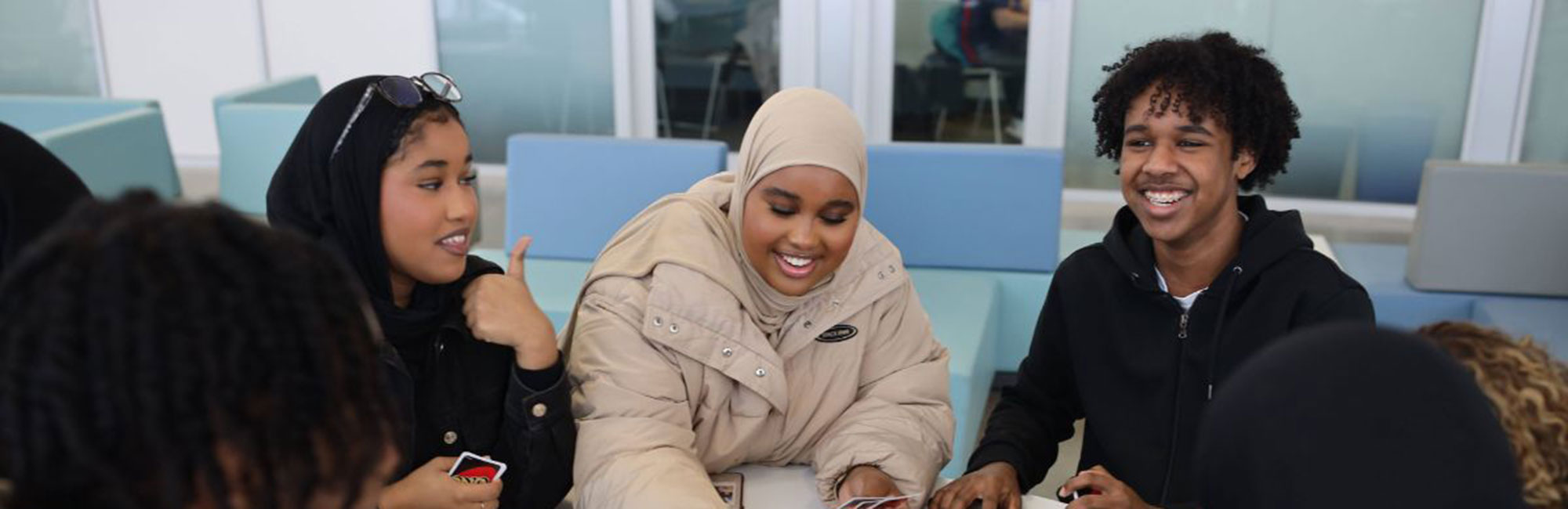 Black students smiling and using a laptop together in an office.