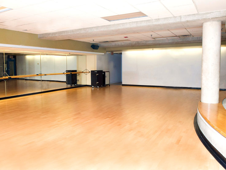 A view of the RAC II studio, including hardwood floor, mirror, and ballet bar