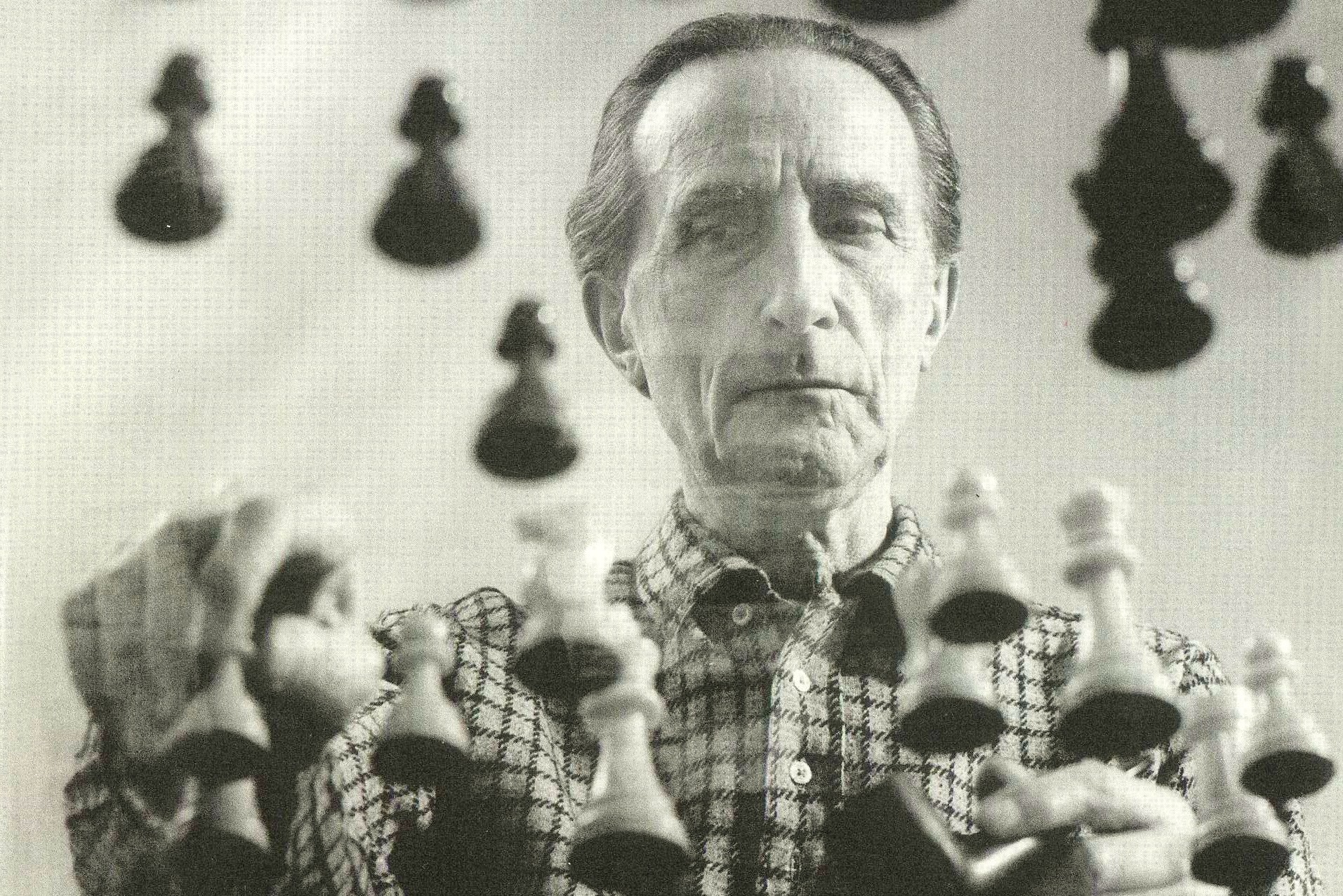 photograph of Marcel Duchamp playing chess. Shot from below a clear glass chess table.