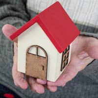 eldery person holding toy house in hand