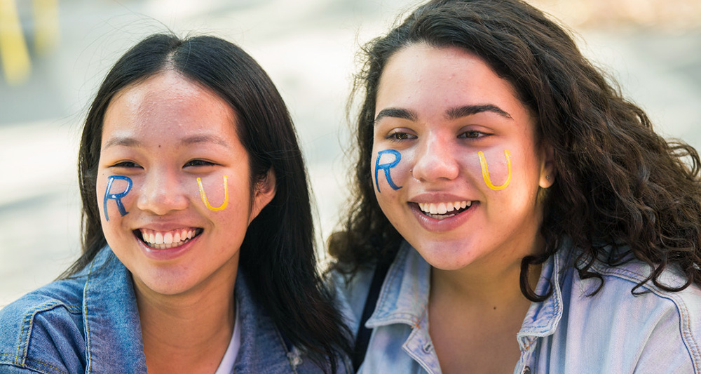 Two students participating in orientation week by having their face painted with Toronto Metropolitan University.
