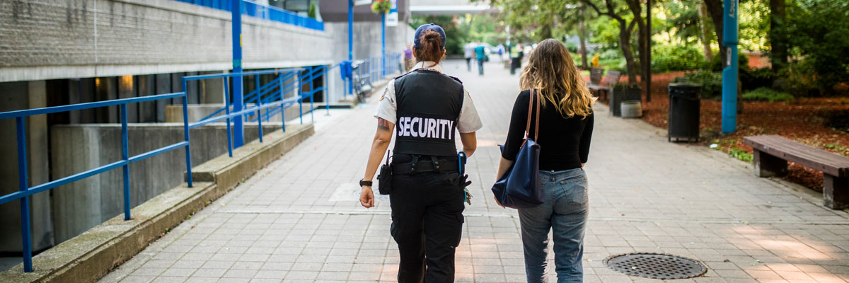 Member of the security team walking with a student on campus.