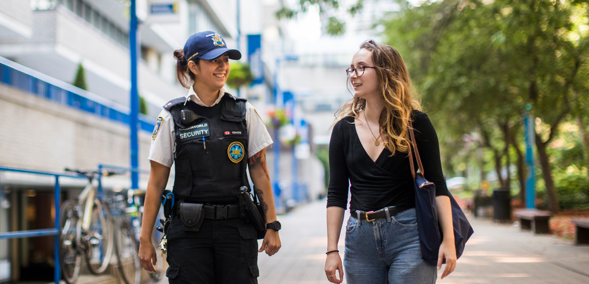 Member of the security team walking with a student.