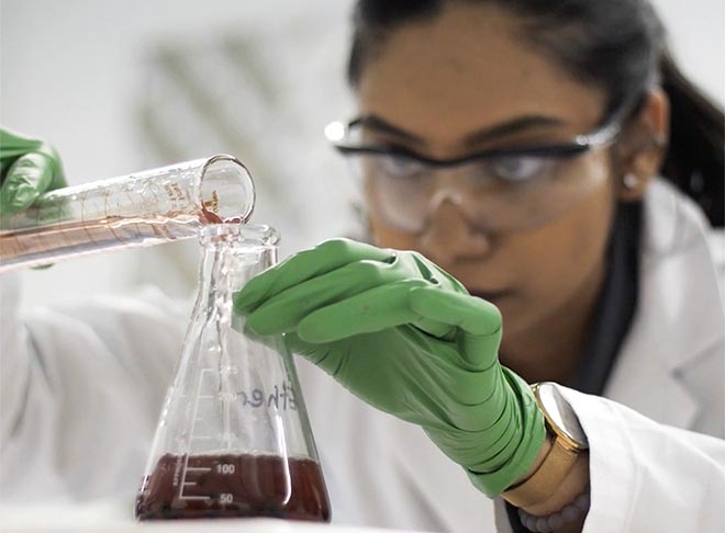 A scientist measuring liquid in a beaker.