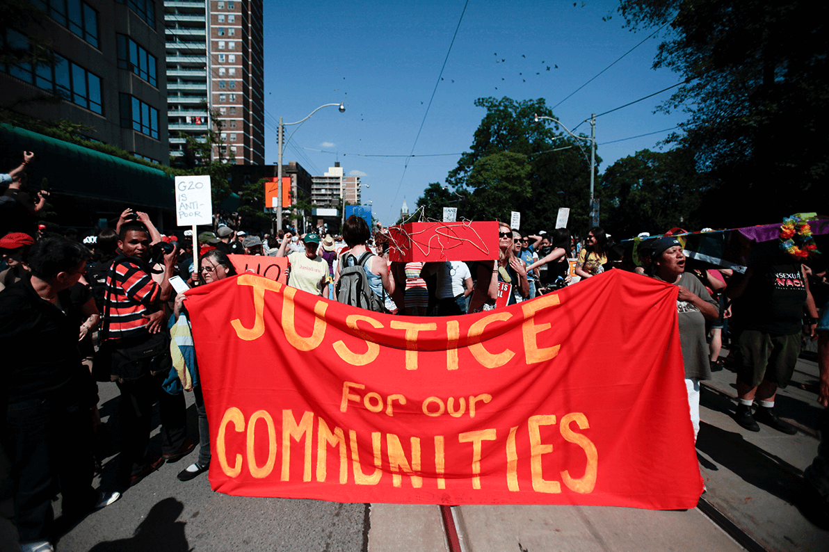 Students marching and holding a large sign displaying "Justice for our communities"