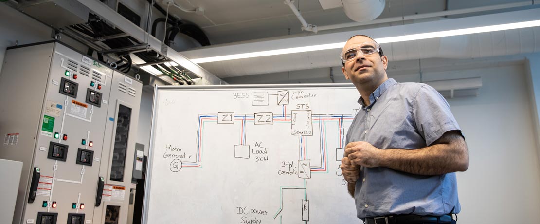 A male researcher in front of a whiteboard with diagrams