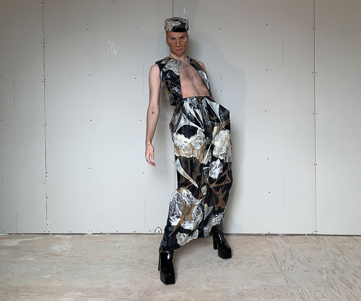 A model is wearing a marbled black and white outfir. There is an open vest and an anckle-length skirt.