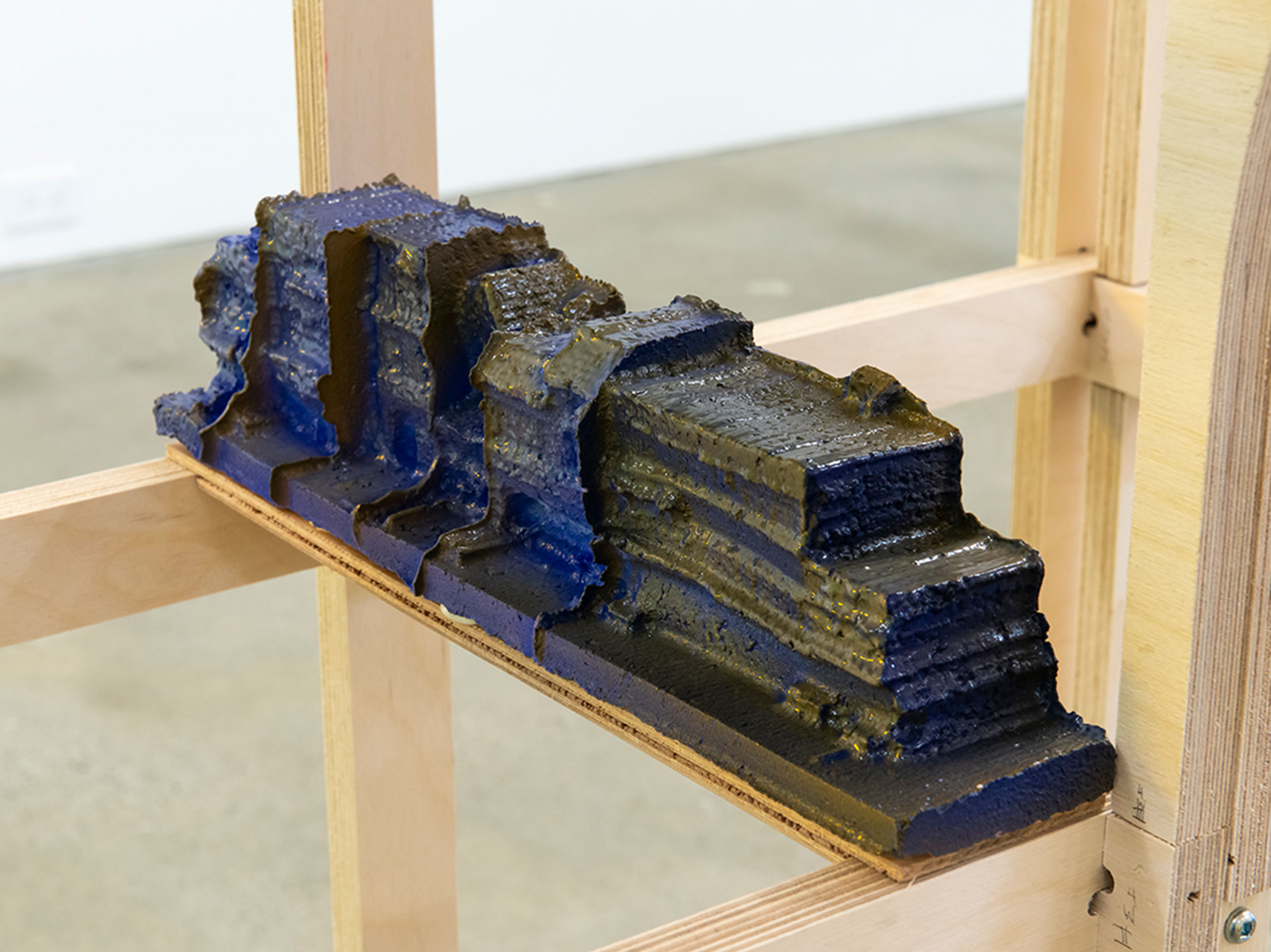 Blocks of blue-glazed ceramic structures resting inside of a wooden frame.