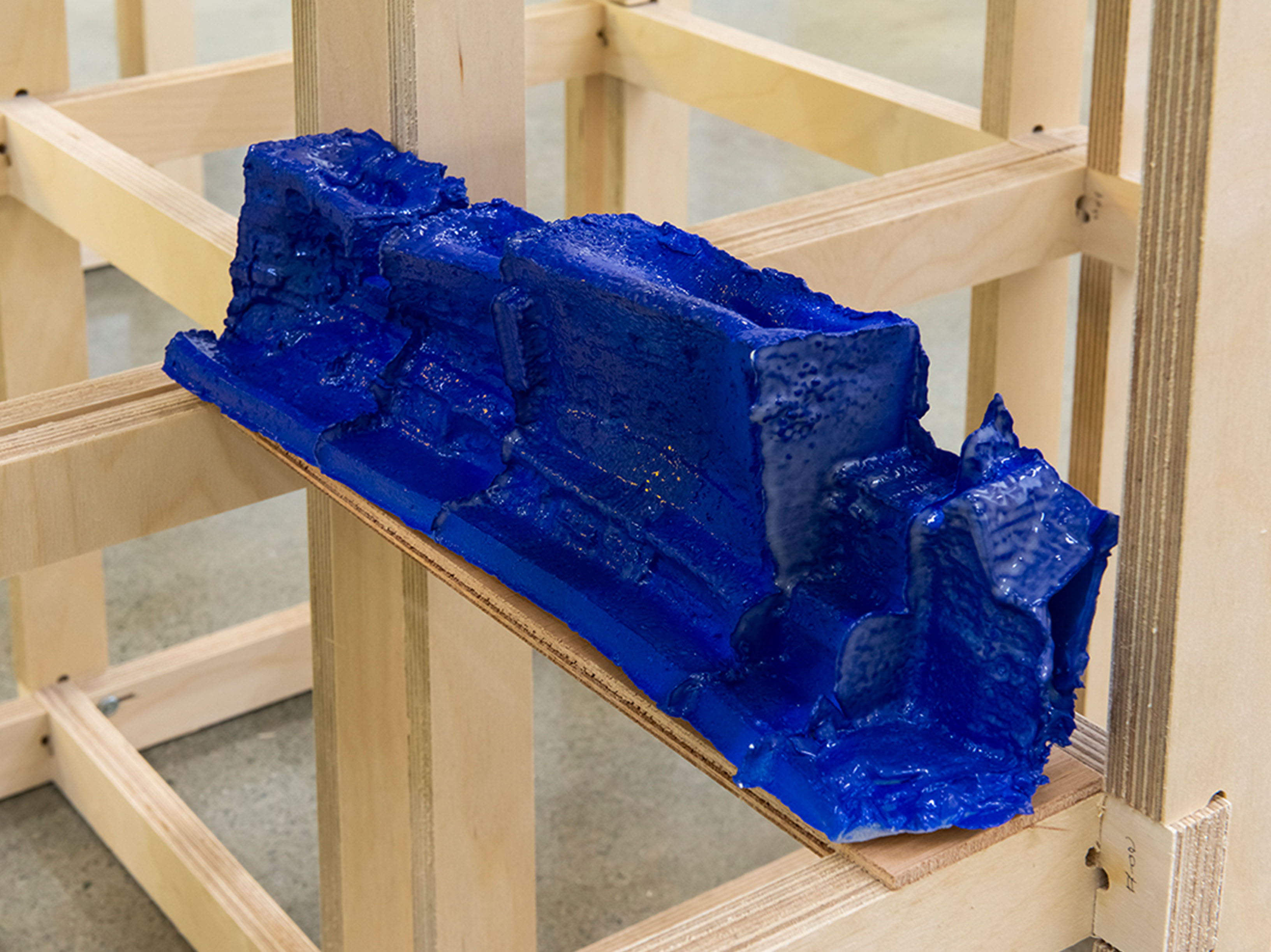 Blue ceramic blocks balancing on a narrow wooden frame.