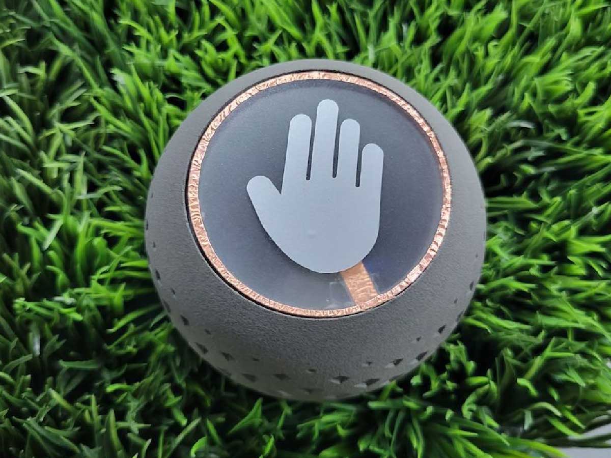A round grey object is surrounded by grass. There is an icon of a hand in the center of the round object.