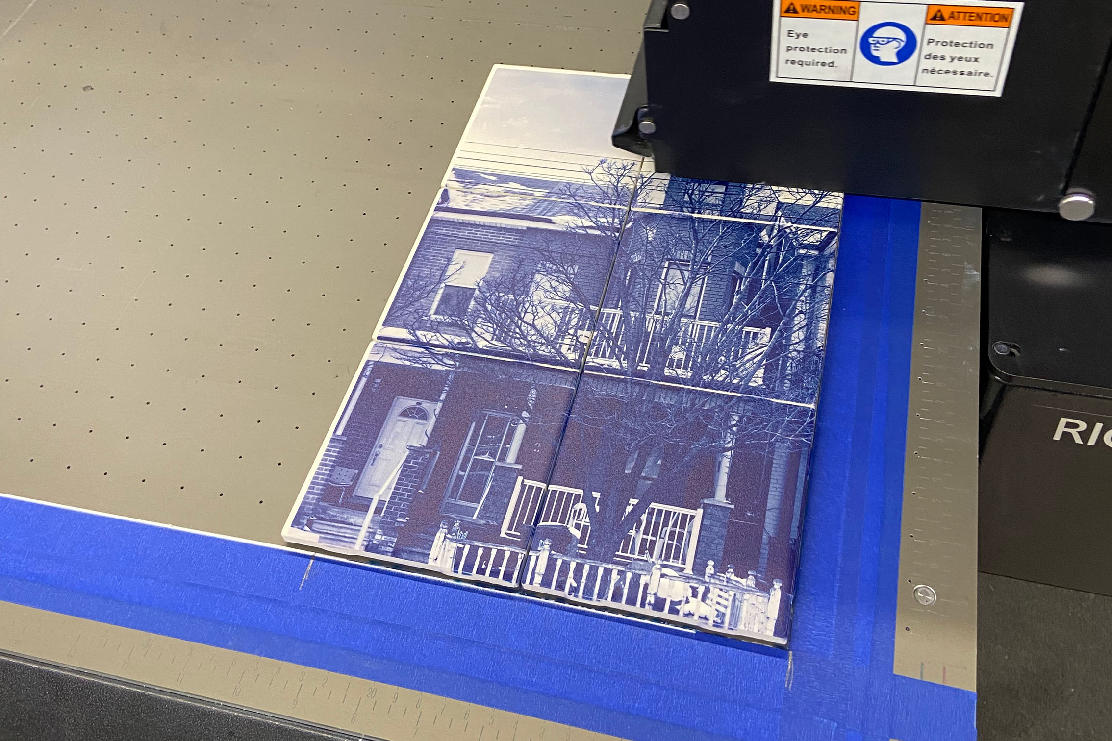 Blue and white printed image of a home on the bed of the RICOH printer. 