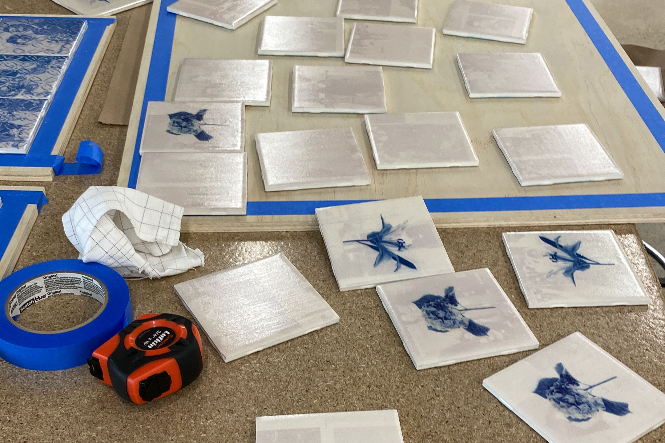 A work station covered in small square tiles . Some tiles have blue and white flowers printed on the surface. 