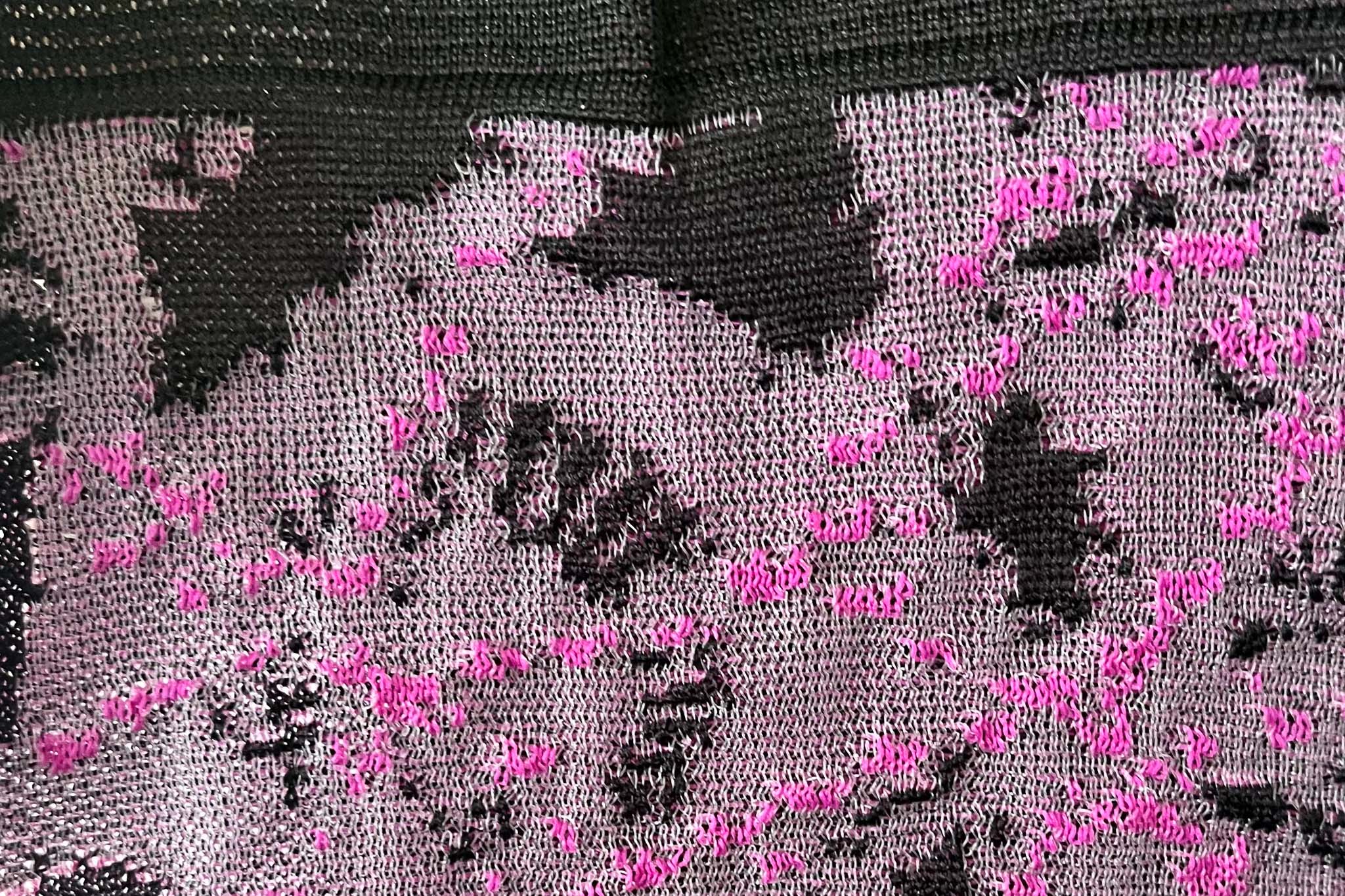 An abstract knit design using light pink, light grey and dark grey threads. 
