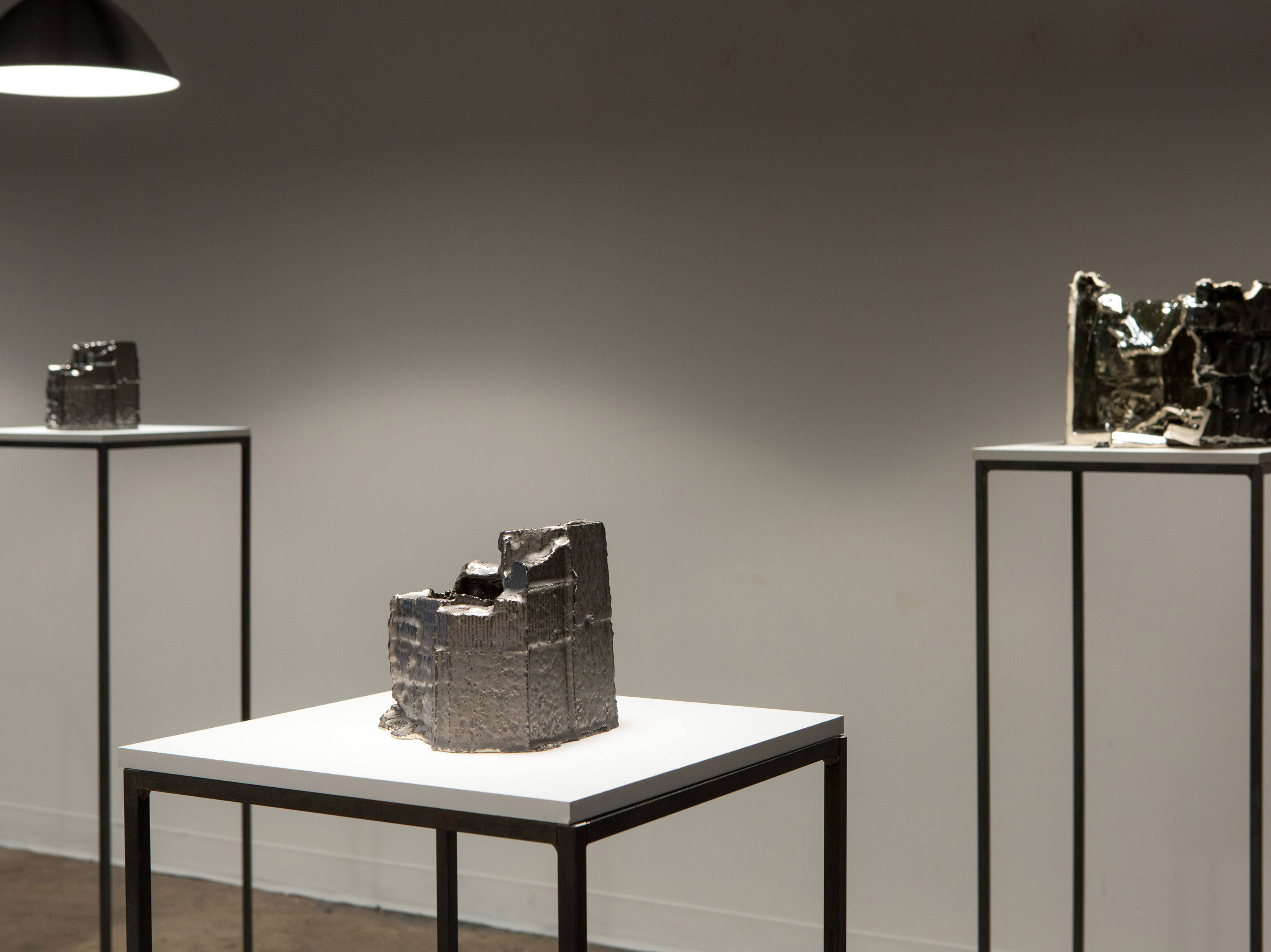 3 plinths in a gallery setting, displaying metallic structures in the shapes of cubes.