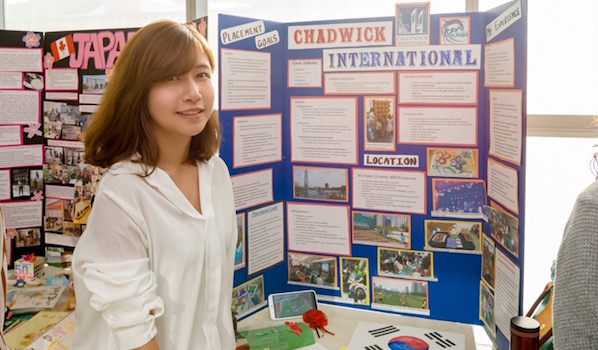 Wendy Ko is standing near the banner of Chadwick International, South Korea