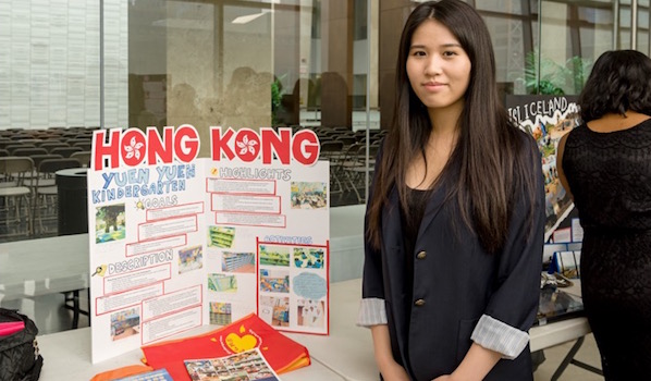 Tiffany Lam is standing near the banner of the Yuen Yuen Kindergarten, Hong Kong