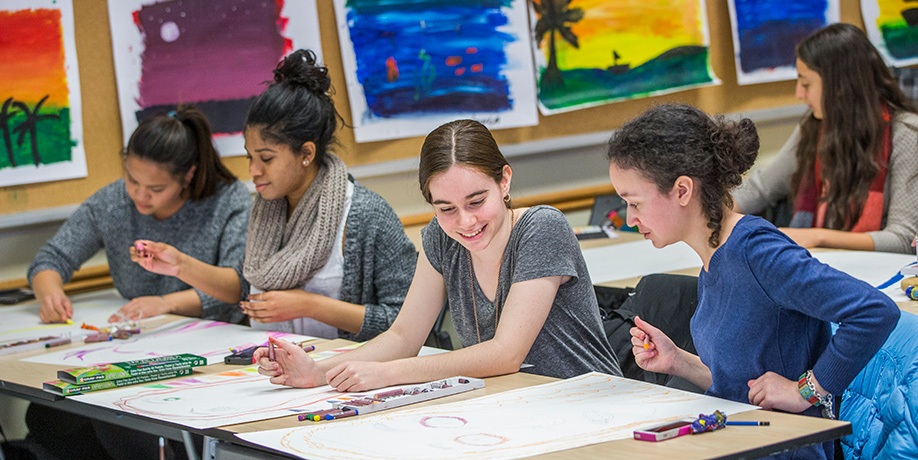 Students sit at desks in art class with drawing materials.