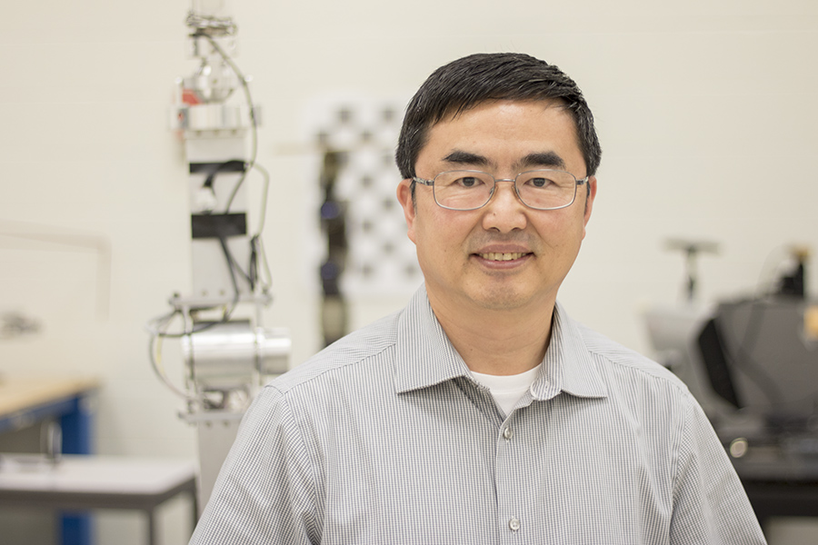 Dr. Guang Jun Liu smiles inside a research lab