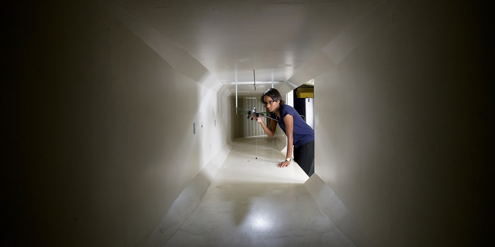 Women holds model airplane inside a wind tunnel