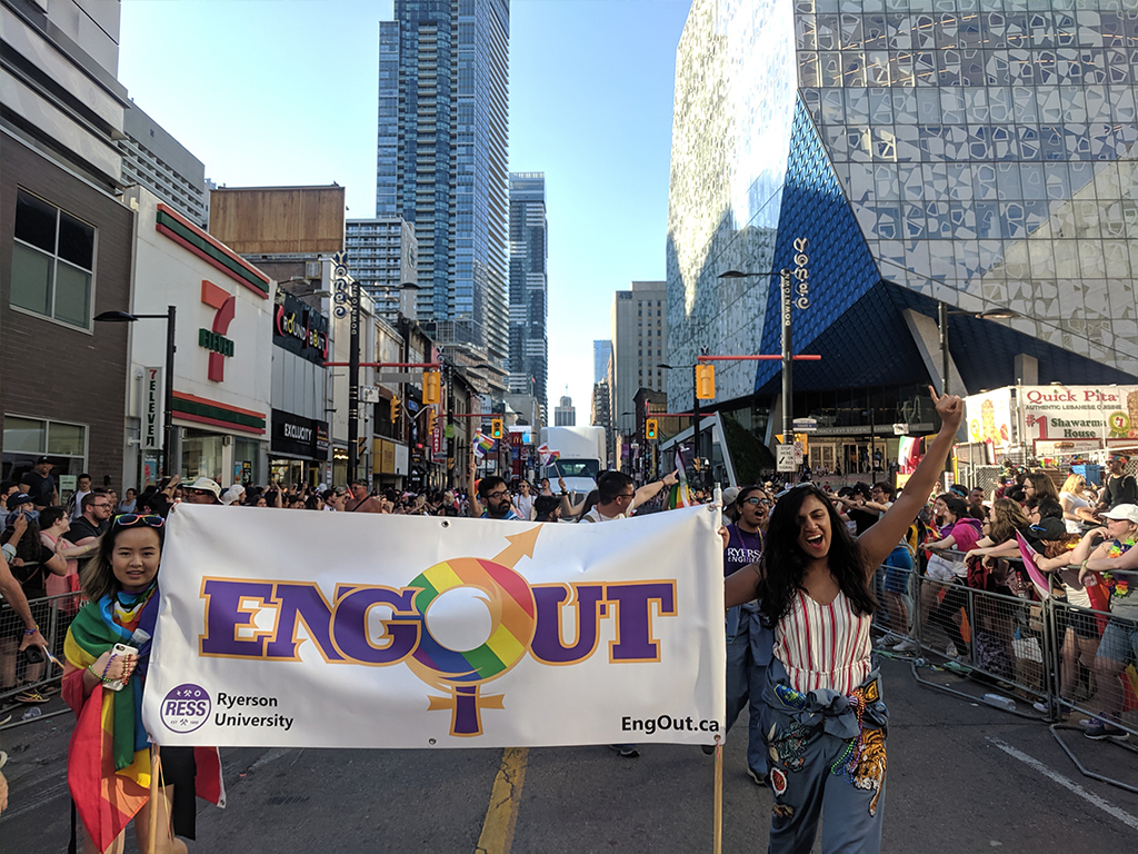 Excited engineering students hold an EngOut banner as they walk in a Pride parade down Yonge Street in Toronto