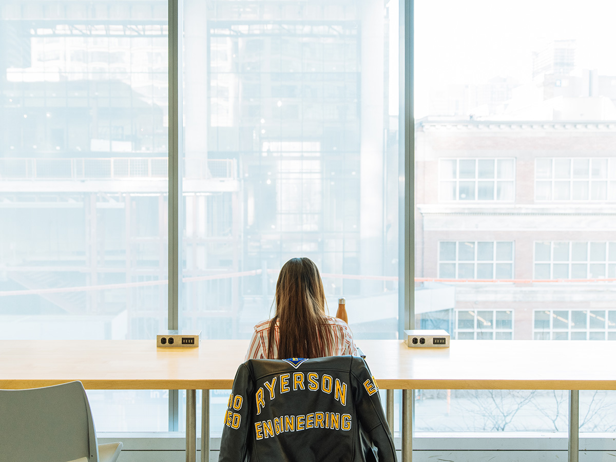 A woman with a Toronto Metropolitan University Engineering jacket studying
