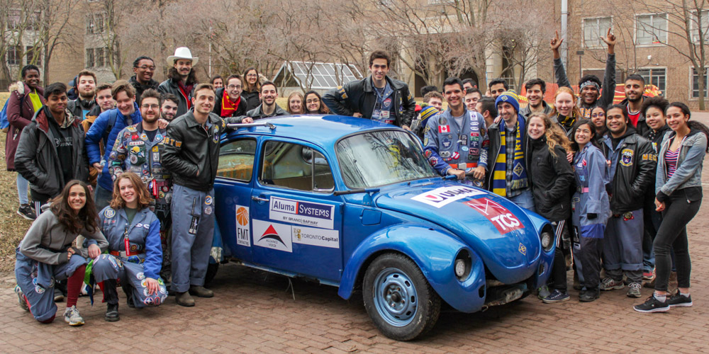 Students posing around a car during Bug Push 2019