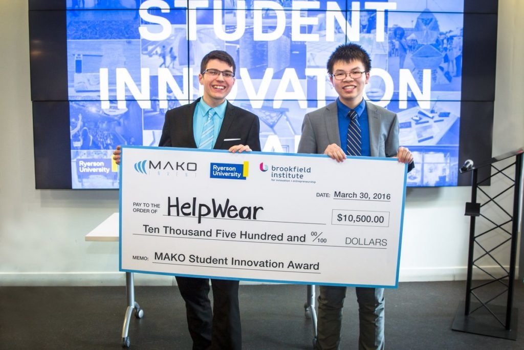 Two happy Ryerson students holding a cheque for ten thousand, five hundred dollars after winning the student innovation competition.