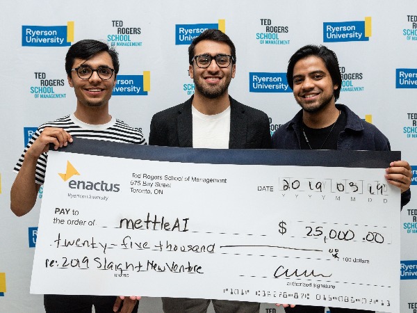 Three Students hold up a cheque of twenty-five thousand dollars after winning the Slaight Competition.