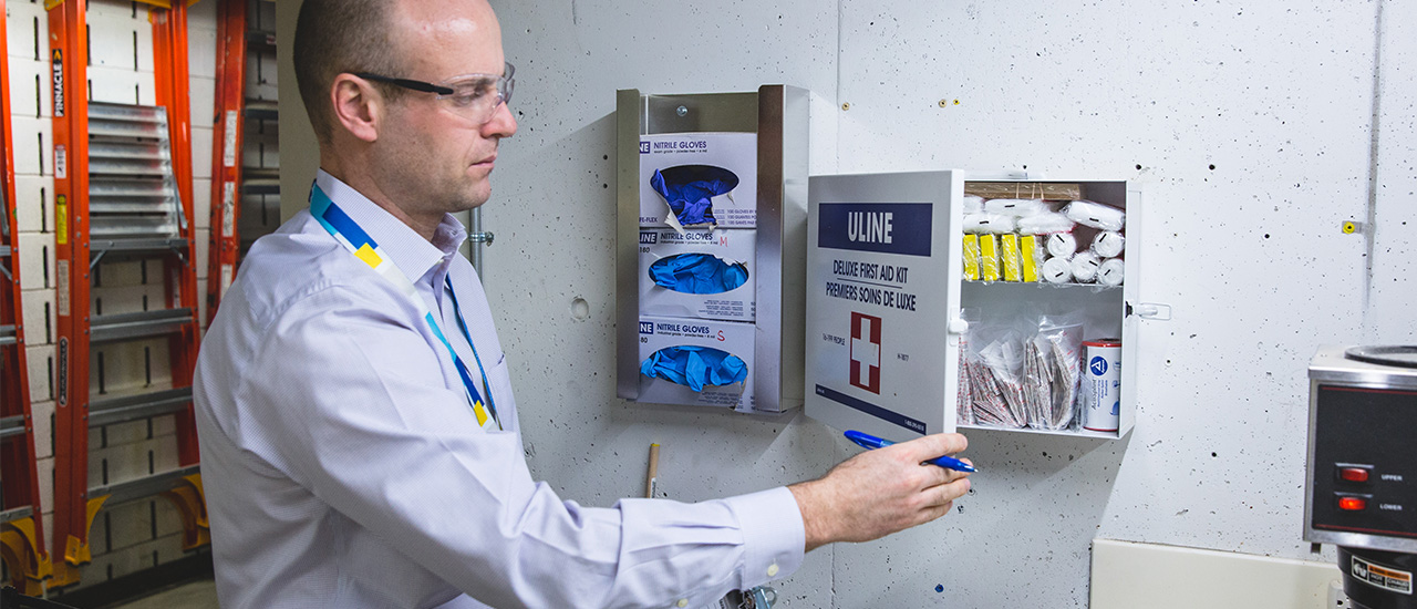 A member of the Environmental Health and Safety team reviewing the contents of a first aid kit. 
