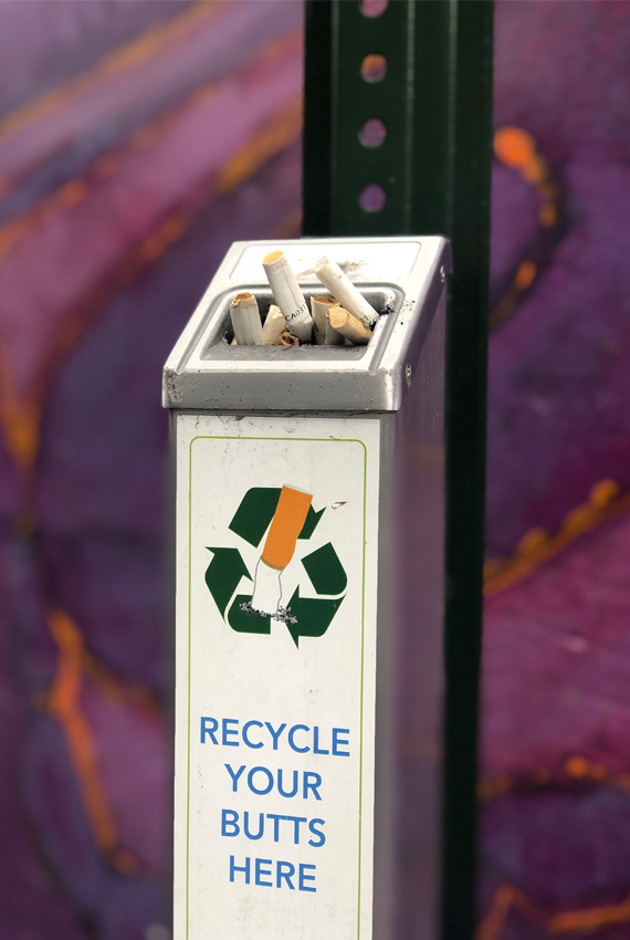 A close-up of a cigarette butt receptacle on a pole.