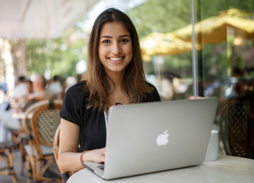 A student sitting at her laptop smiling.