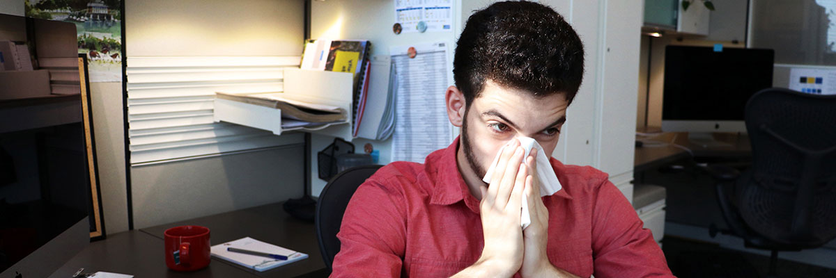 Person with a cold, blowing their nose into tissue.