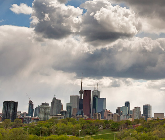 Toronto skyline with dramatic grey clouds and a blue sky.