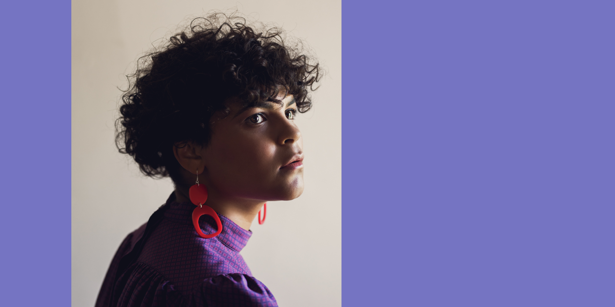 A model gazing away from the camera wearing red droplet earrings designed by contemporary Indigenous designer and Alumnus, Warren Steven Scott.