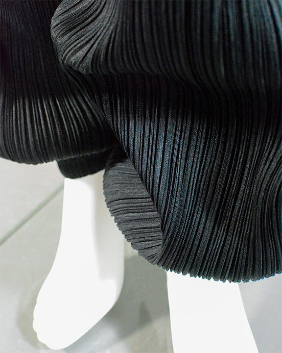 Close up of leg of black pleated Issey Miyake Trousers