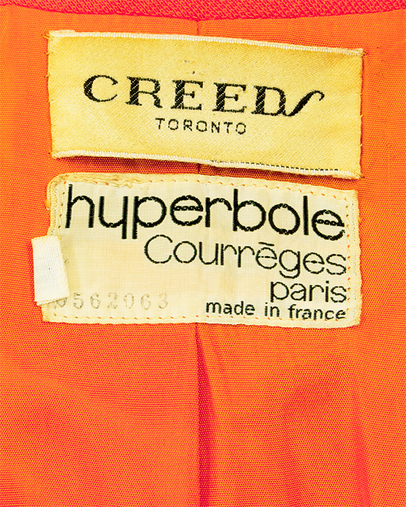 Label of an orange Courreges jumpsuit. Label reads Creeds Toronto, Hyperbole Courreges, Paris Made in France