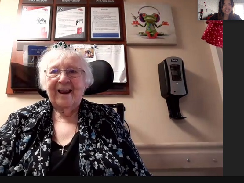 A happy senior smiles while looking into a web cam